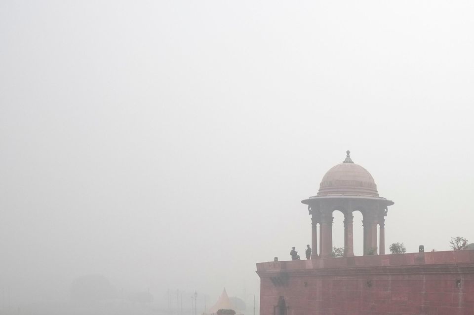 An office goer walks wearing a face mask amid a thick layer of smog in New Delhi (Manish Swarup/AP)