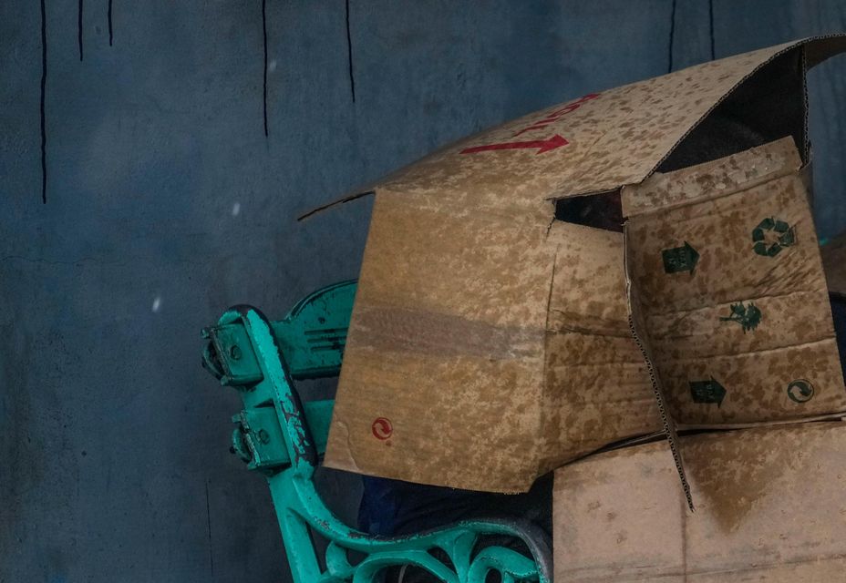 People at a bus stop shield themselves with cardboard from the wind and rain during the passage of Hurricane Rafael in Havana, Cuba (Ramon Espinosa/AP)