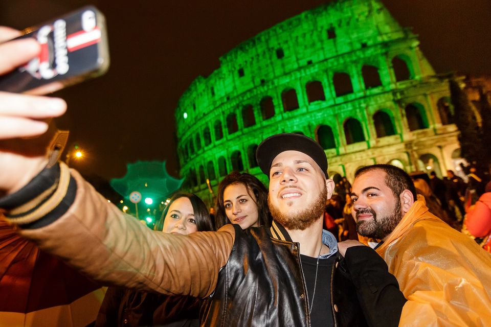 People in Rome taking selfies in front of the ‘greened’ Colosseum.