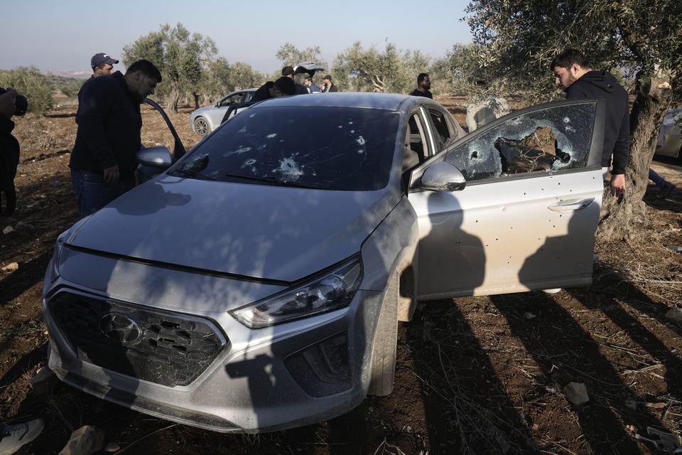 People inspect a car riddled with bullet holes after an Israeli army incursion in the village of Qusra, near Jenin, in the occupied West Bank on Sunday (Majdi Mohammed/AP)