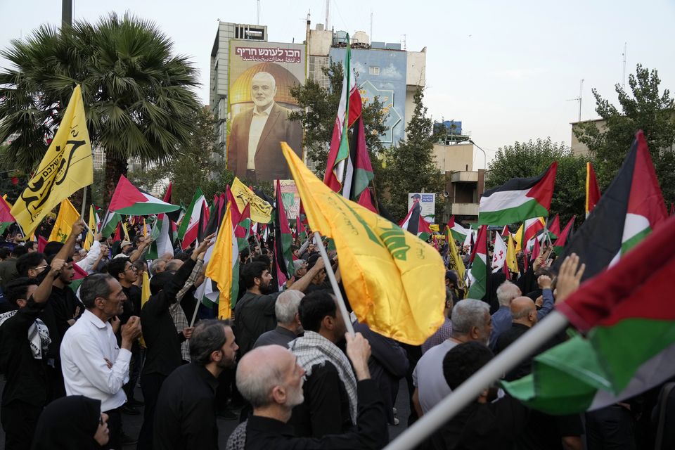 Iranian protesters wave Iranian, Palestinian and Lebanon’s militant Hezbollah group flags in a demonstration to condemn the killing of Hamas leader Ismail Haniyeh at Felestin (Palestine) Square in Tehran (Vahid Salemi/AP)