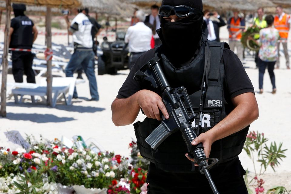 A hooded Tunisian police officer stands guard ahead of the visit of top security officials of Britain, France, Germany and Belgium at the scene of Friday's shooting attack in front of the Imperial Marhaba hotel in the Mediterranean resort of Sousse, Tunisa, Monday, June 29, 2015. The top security officials of Britain, France, Germany and Belgium are paying homage to the people killed in the terrorist attack on Friday. (AP Photo/Abdeljalil Bounhar)