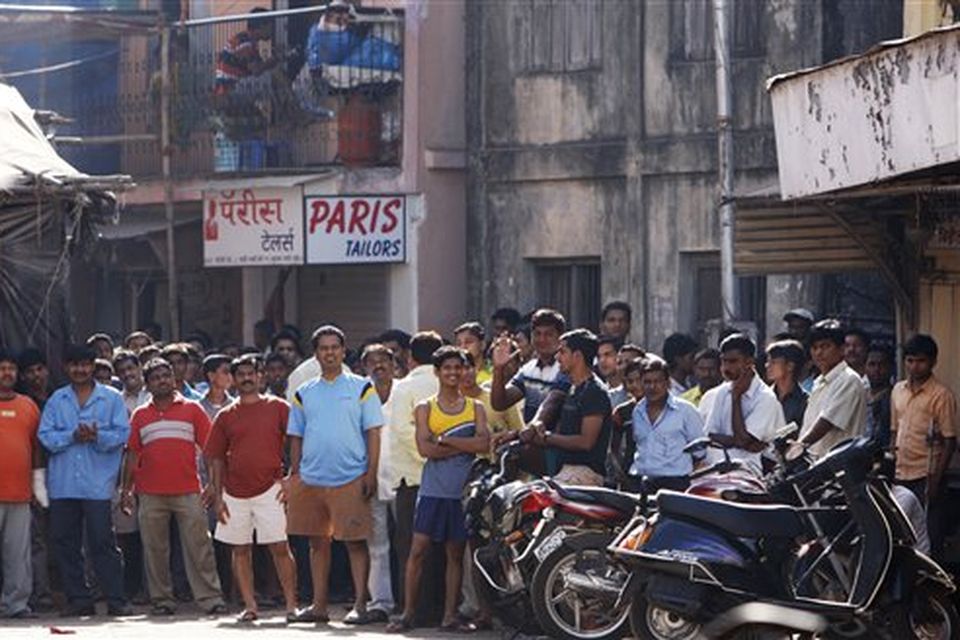 Local people gather to watch action as policemen and commandoes surround an apartment where suspected gunmen have held a family hostage in Colaba, Mumbai, India, Thursday, Nov. 27, 2008. Teams of gunmen stormed luxury hotels, a popular restaurant, hospitals and a crowded train station in coordinated attacks across India's financial capital, killing at least 101 people, taking Westerners hostage and leaving parts of the city under siege Thursday, police said. A group of suspected Muslim militants claimed responsibility. (AP Photo/Saurabh Das)