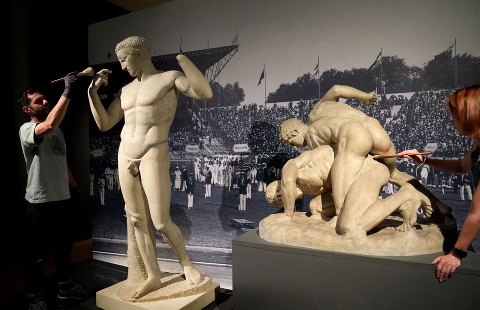 Technicians dust a work which is on display at the Paris 1924: Sport, Art and the Body exhibition at Fitzwilliam Museum (Joe Giddens/PA)