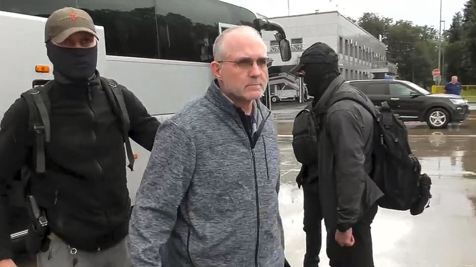 Paul Whelan, centre, is escorted by Russian Federal Security Service agents as they arrive at an airport outside Moscow (Russian Federal Security Service/RTR via AP)