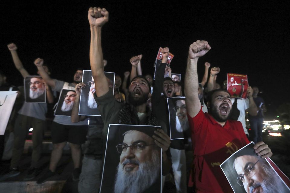 Lebanese and Palestinian men hold portraits of Hezbollah leader Sayyed Hassan Nasrallah, as they shout slogans during a protest in the southern port city of Sidon, Lebanon (Mohammed Zaatari/AP)