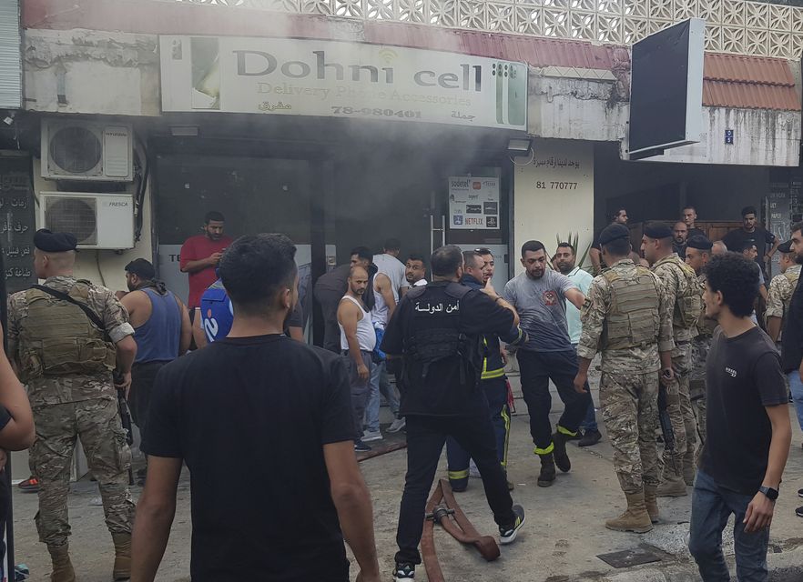 Lebanese soldiers and firefighters gather outside a mobile shop which is believed to have been damaged when a walkie-talkie exploded in the southern port city of Sidon (AP Photo/Mohammed Zaatari)