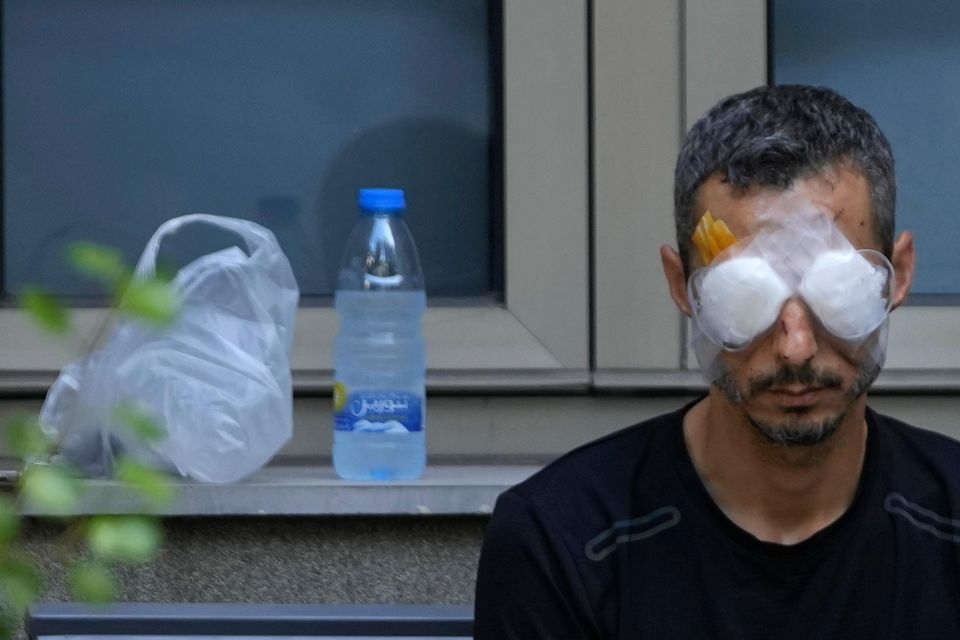 A man who was injured by one of the handheld exploding devices sits outside a hospital as he waits for treatment in Beirut (Hussein Malla/AP)