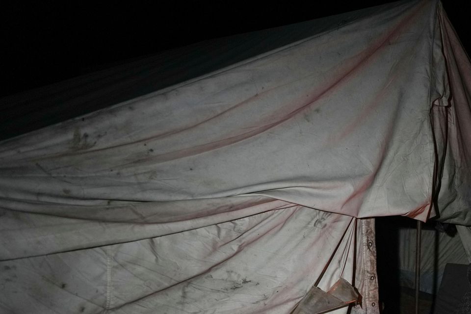 A displaced family sit round the fire in their tent at a camp in Deir al-Balah, Gaza Strip (Abdel Kareem Hana/AP)