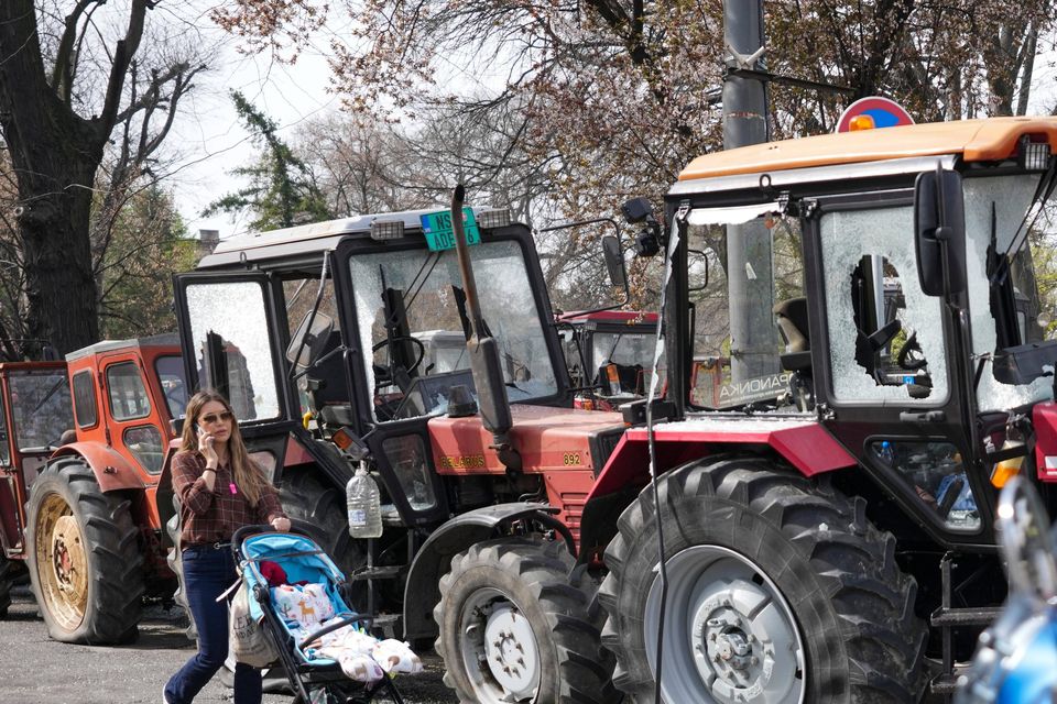 People pass by students and former paramilitary fighters loyal to President Aleksandar Vucic at a camp outside the presidency building prior to a major anti-corruption rally (Darko Vojinovic/AP)