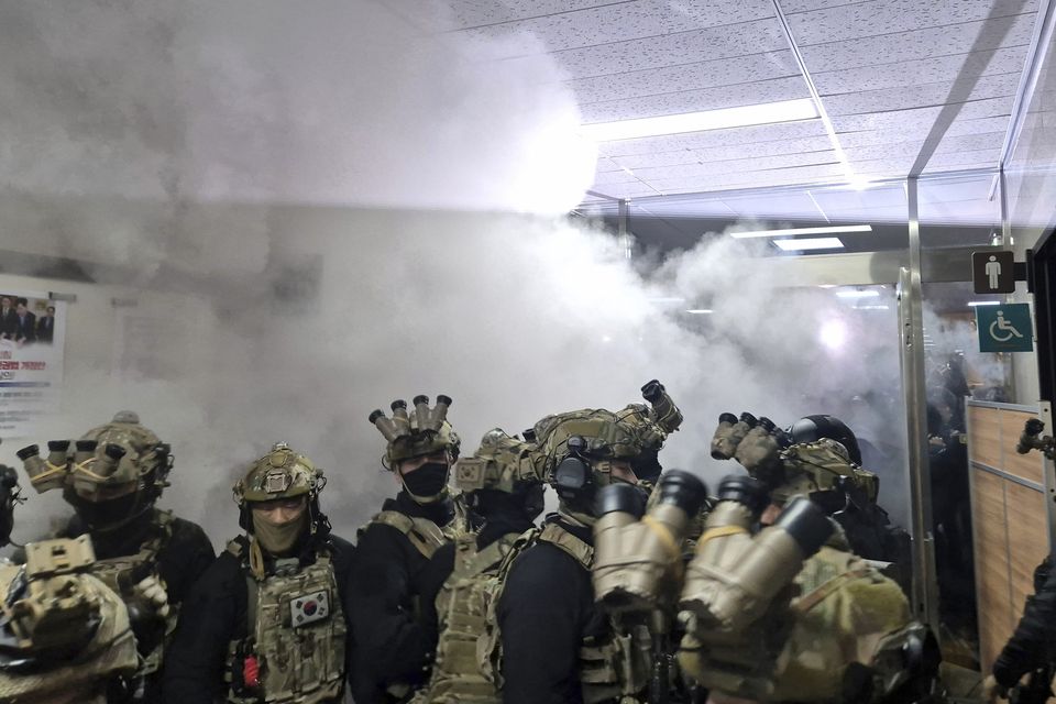 A National Assembly staff member sprays fire extinguishers to block soldiers entering the main hall of the National Assembly in Seoul, South Korea (Jo Da-un/Yonhap via AP)