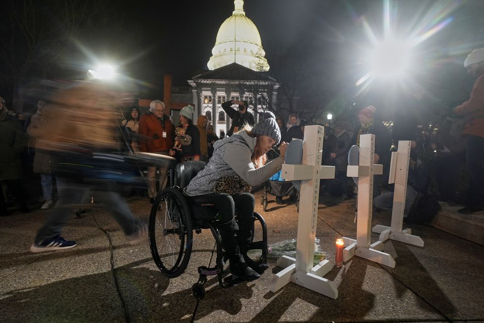 A supporter signs a cross during a candlelight vigil outside the Wisconsin Capitol in Madison (Morry Gash/AP)