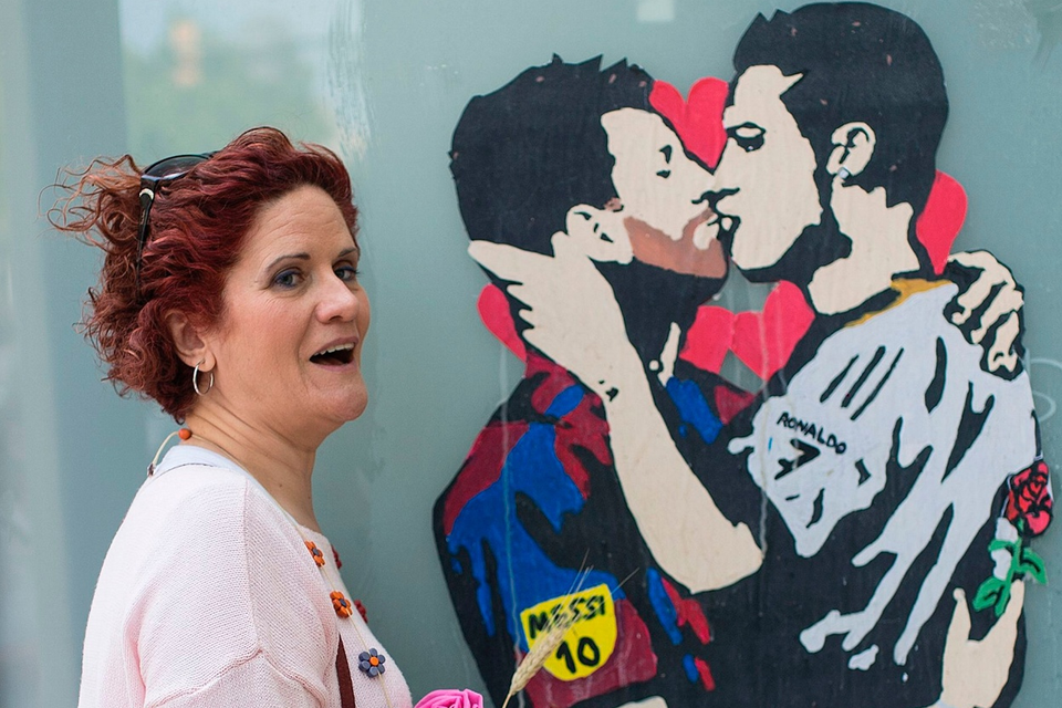 The beautiful game - football fans from around the world -  A woman holding a rose poses with the piece of street art titled Love is blind, depicting Barcelona's Lionel Messi and Real Madrid's Cristiano Ronaldo kissing by street artist Salva Tvboy, in Barcelona on April 23, 2017.