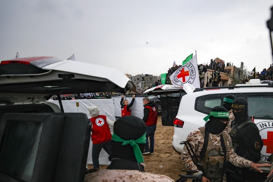 Hamas fighters hand over coffins containing the bodies to the Red Cross in Khan Younis (Jehad Alshrafi/AP)