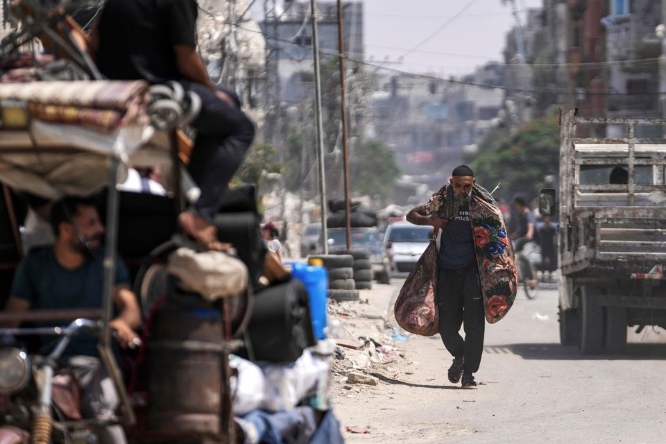 A Palestinian carries his belongings as he evacuates Maghazi refugee camp in Gaza, as part of a mass evacuation ordered by the Israeli military ahead of an operation (Abdel Kareem Hana/AP)