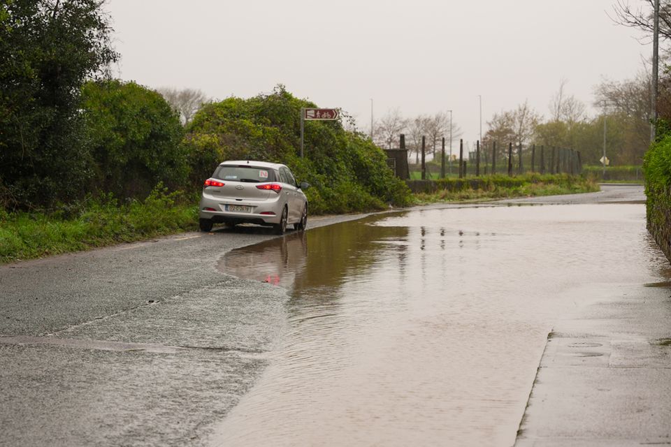 A car is driven past a flooded road at Passage West, Co Cork (Noel Sweeney/PA)