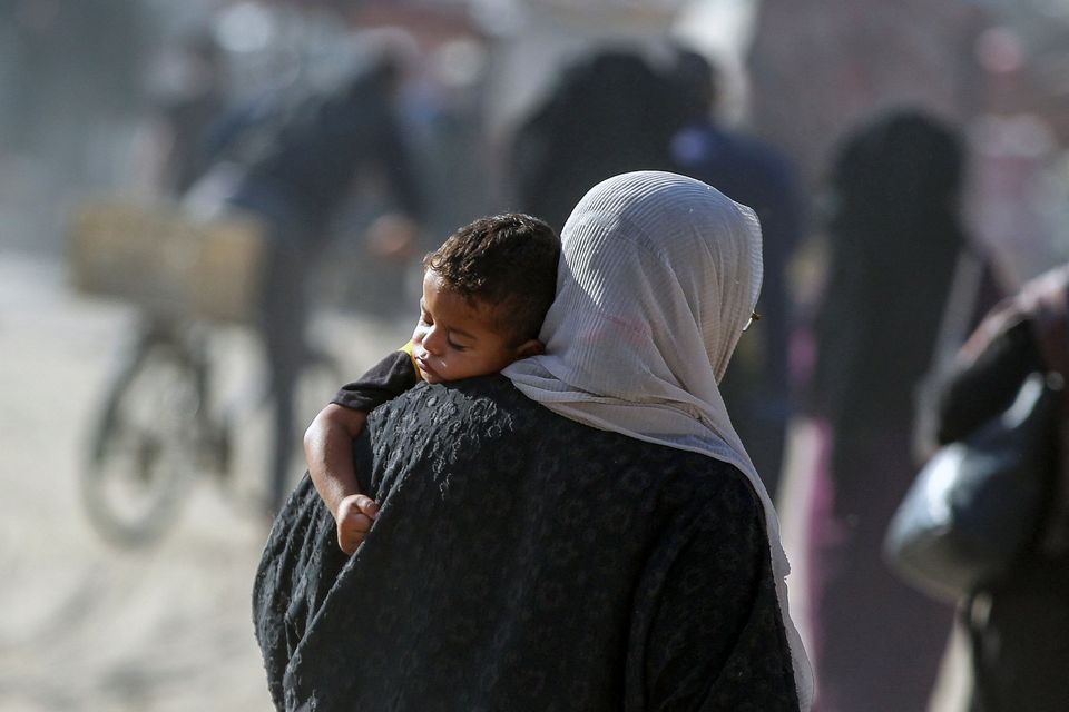 A displaced Palestinian woman carries a child as she makes her way to flee areas in the eastern part of Khan Younis following an Israeli evacuation order. Photo: Reuters