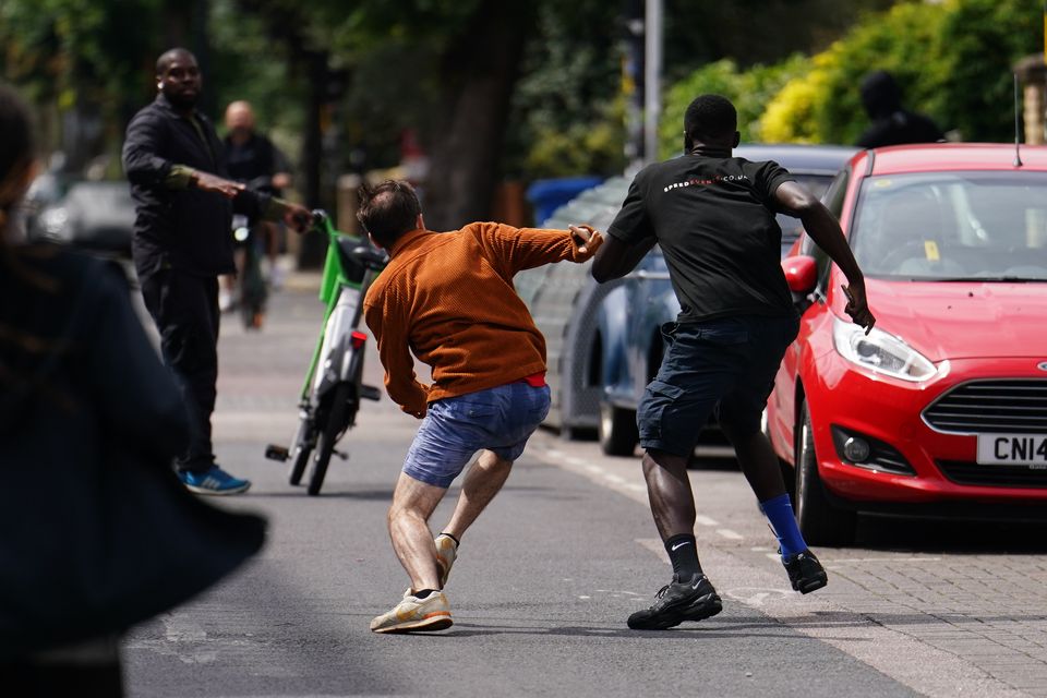 A man chases people thought to have removed a new ‘howling wolf’ artwork by Banksy from a shop roof in Peckham (Jordan Pettitt/PA)