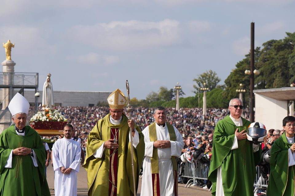 A priest carrying a Portuguese National Republican Guard motorcyclist helmet walks ahead of the Our Lady of Fatima statue in a procession starting the IX Pilgrimage of the Blessing of Helmets at the Roman Catholic holy shrine of Fatima (Ana Brigida/AP)