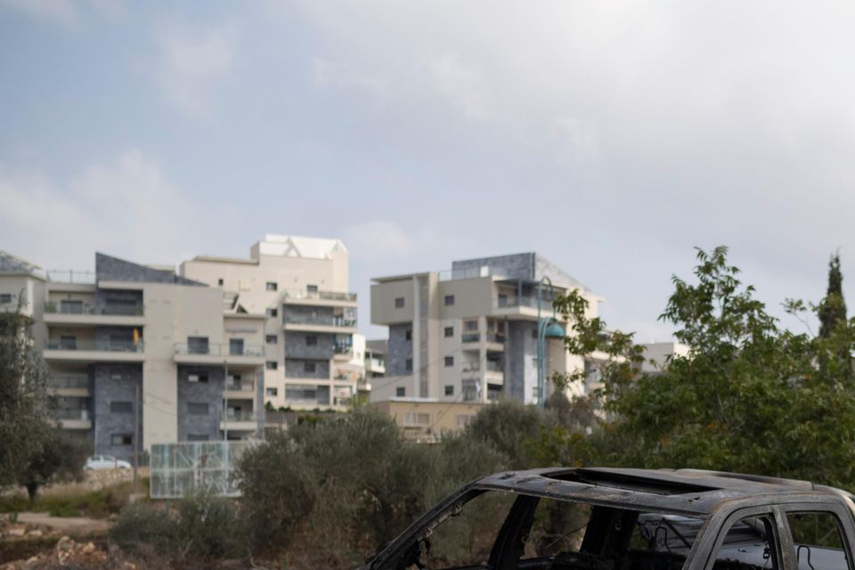 A man shows a girl a burnt-out car after a rocket launched from Lebanon hit an area in Kfar Vradim, northern Israel (Leo Correa/AP)