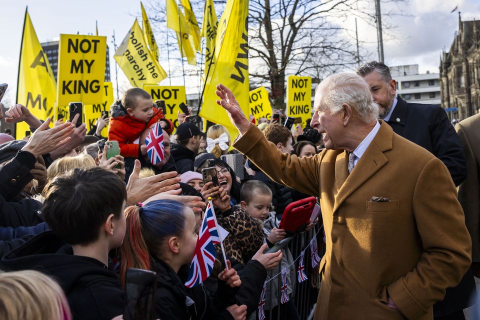 The King meets members of the public, with some anti-monarchy protesters in the background (James Glossop/The Times/PA)