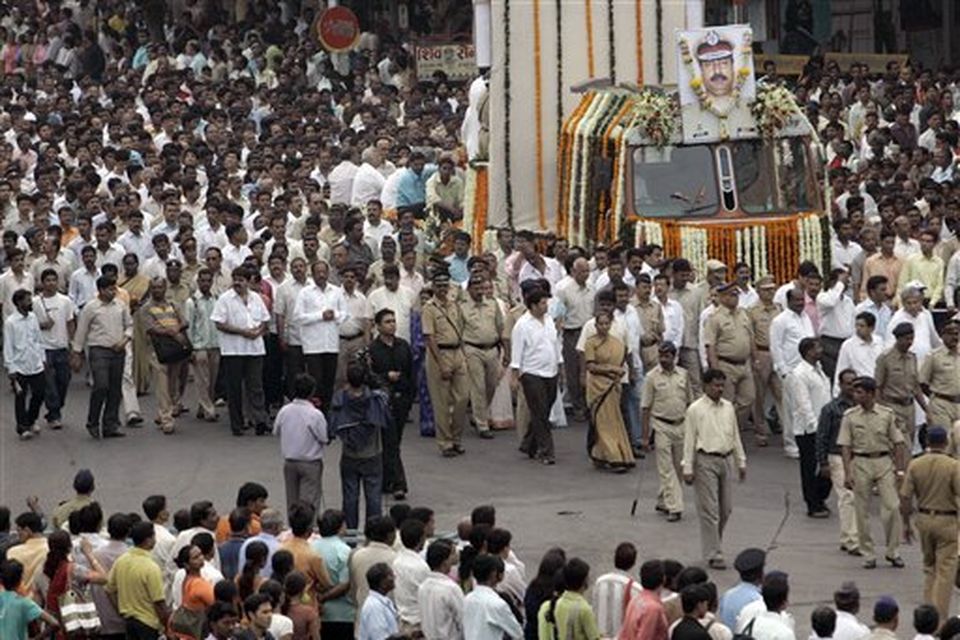 Citizens and police officers walk during the funeral procession of Hemant Karkare, the chief of Mumbai's Anti-Terrorist Squad, who was killed by gunmen, his photo seen at right top, in Mumbai, India, Saturday, Nov. 29, 2008. Indian commandos killed the last remaining gunmen holed up at a luxury Mumbai hotel Saturday, ending a 60-hour rampage through India's financial capital by suspected Islamic militants that killed people and rocked the nation. (AP Photo/Rajanish Kakade)