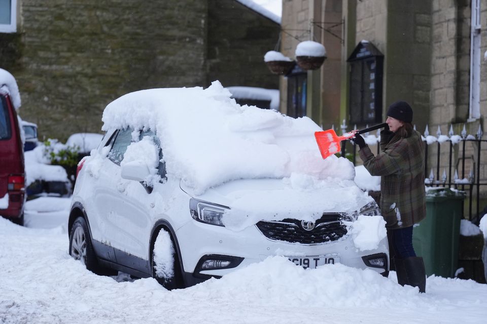 A man clears snow from a car in Allendale, Northumberland (Owen Humphreys/PA)