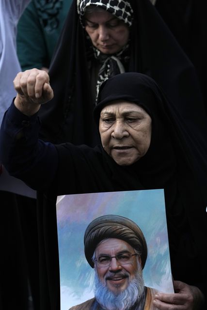 A demonstrator chants as she holds a poster of killed Hezbollah leader Hassan Nasrallah (Vahid Salemi/AP)