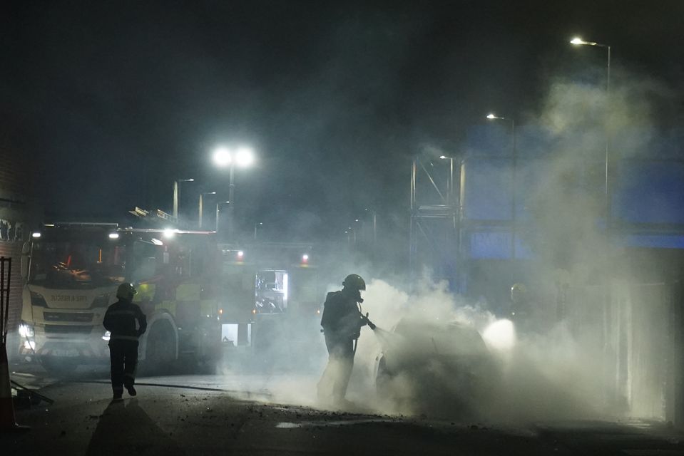 Firefighters tend to a burning police car burns as officers are deployed on the streets of Hartlepool following a violent protest (Owen Humphreys/PA)