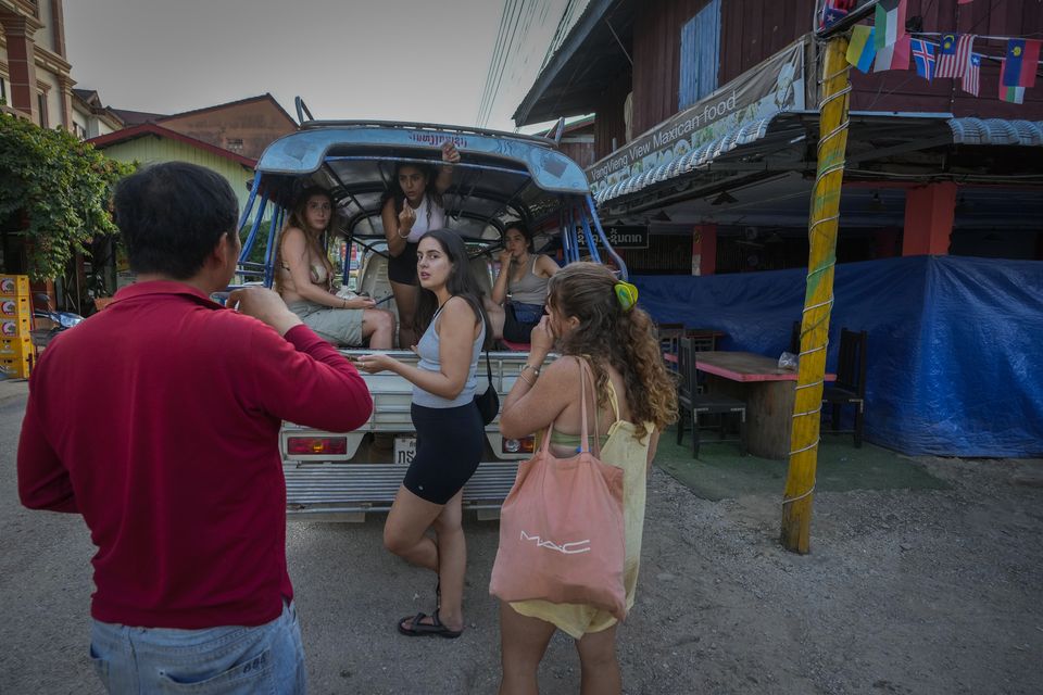 Tourists talk to a bar owner in Vang Vieng, Laos (Anupam Nath/AP)