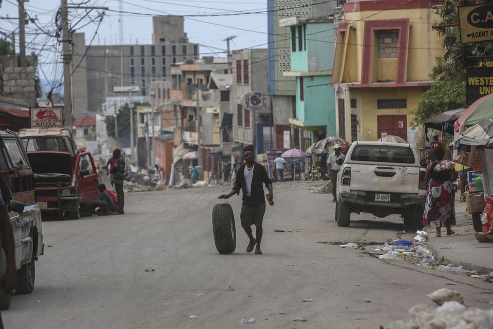 A man rolls a tyre as walks along a street in Port-au-Prince, Haiti (AP Photo/Odelyn Joseph)