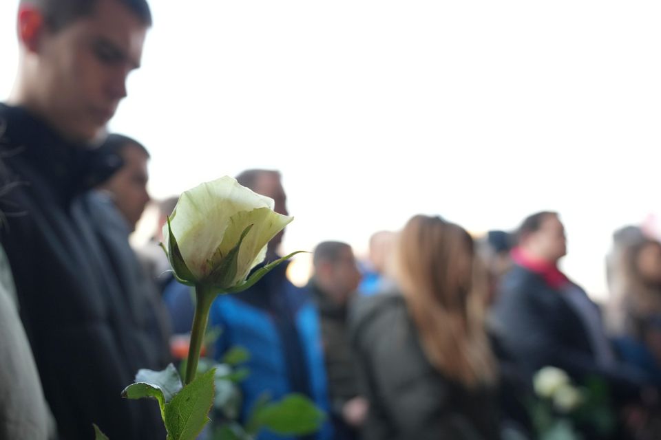 Students hold white flowers in front of the court building (Darko Vojinovic/AP)