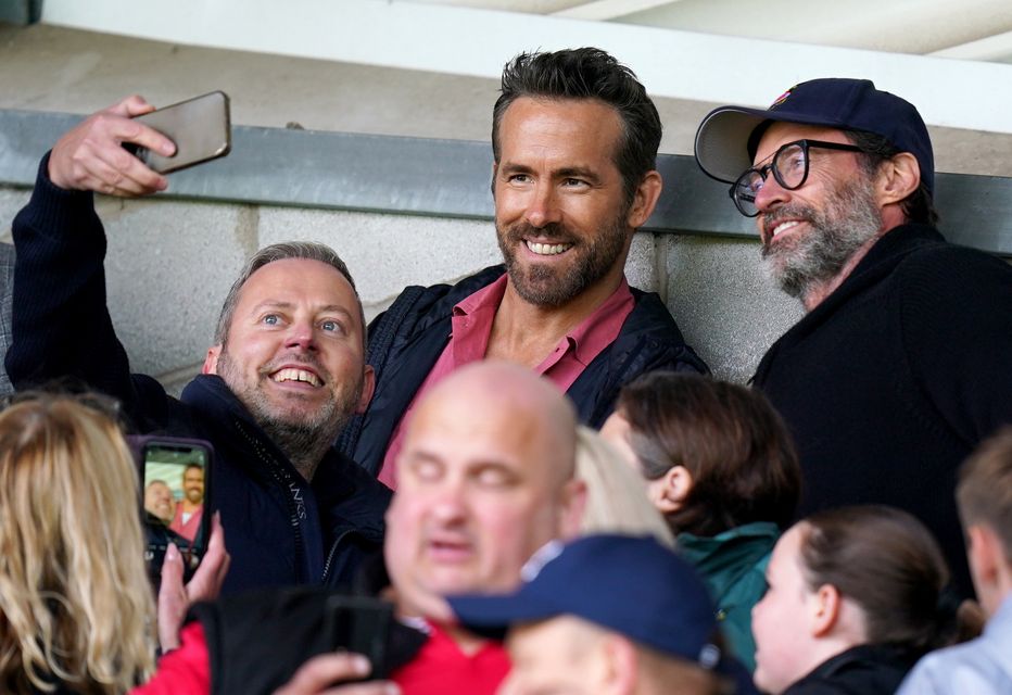 Hollywood actor Hugh Jackman (right) and Ryan Reynolds pose for a photo with a fan at a Wrexham game (Jacob King/PA)