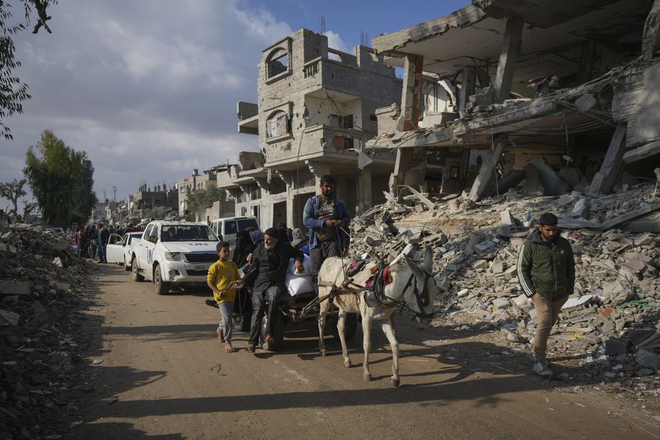 Palestinians carry UN-donated flour in Khan Younis, in central Gaza, on Saturday (Abdel Kareem Hana/AP)