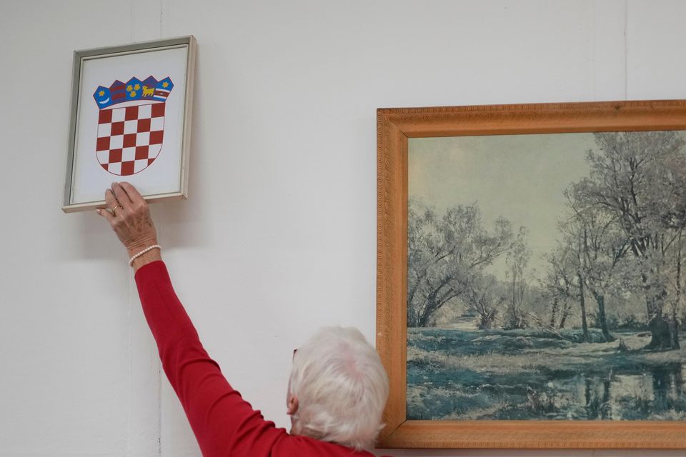 A member of the election commission sets the coat of arms at a polling station in Zagreb (Darko Bandic/AP)