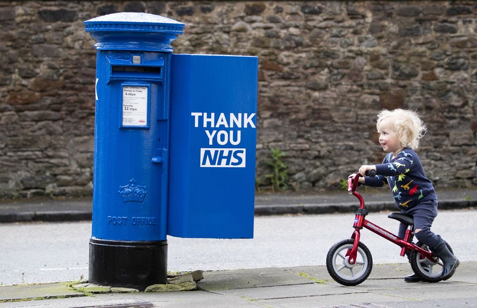 Xander Irvine, three, cycles past a post box celebrating the NHS – two months before he died (Jane Barlow/PA)