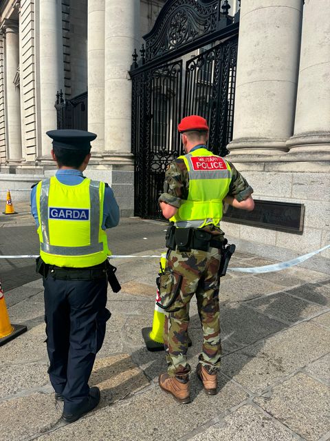 A Garda officer and a military police officer look at damage caused to gates outside Government Buildings in Merrion Street, Dublin, after they were struck by a van in the early hours of Thursday morning.  Cate McCurry/PA Wire