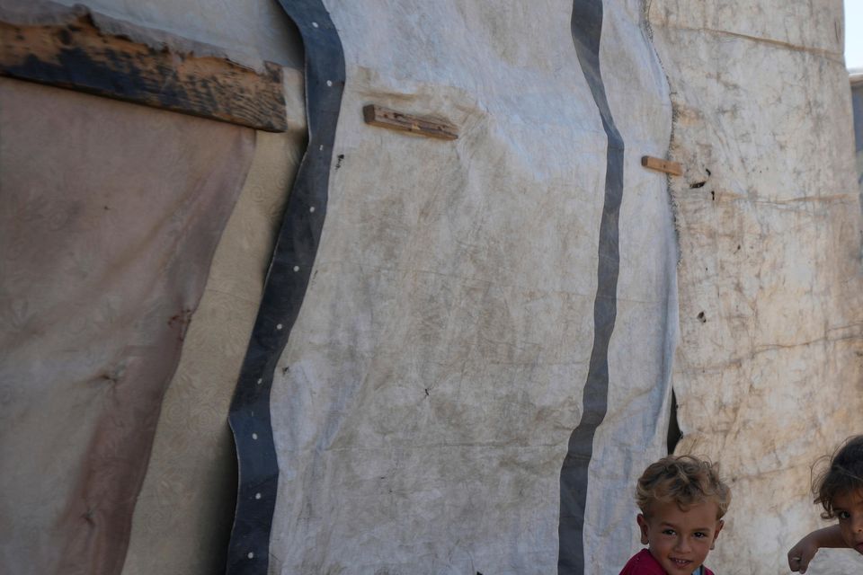 Displaced Palestinian children sit next to their tent in Deir al-Balah in the Gaza Strip (Abdel Kareem Hana/AP)