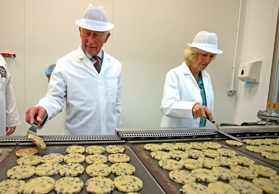 The then-Prince of Wales and Duchess of Cornwall flipping Welsh cakes on hot plates during their tour of the Village Bakery in Wrexham in 2015 (Peter Byrne/PA)