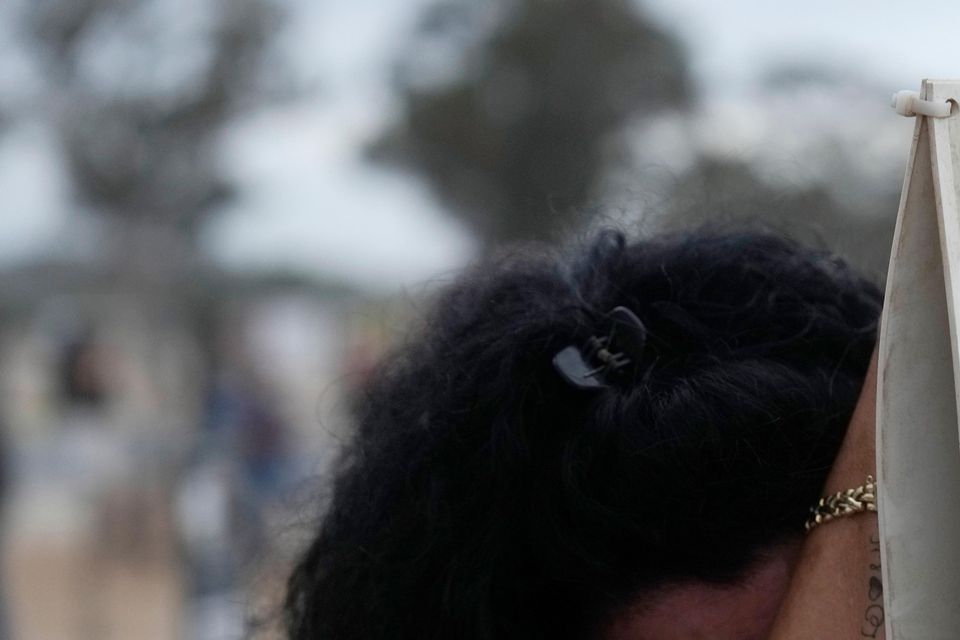 A woman leans on a picture of Mapal Adam, at the site of the Nova music festival (Ariel Shalit/AP)