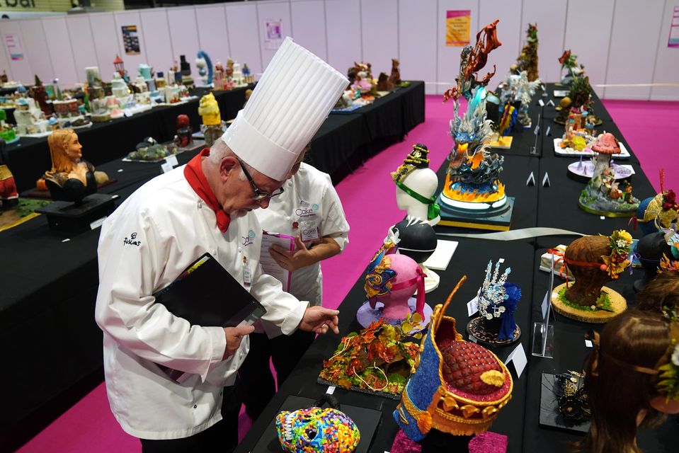 Judges examine a selection of cakes on display (Jacob King/PA)