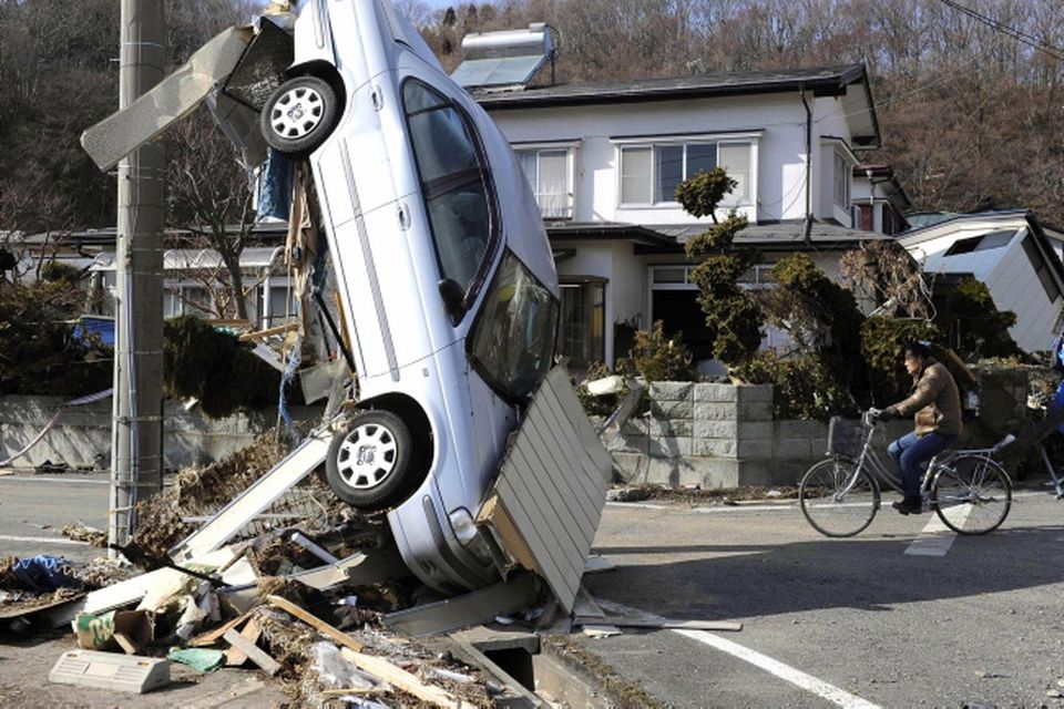 A car leans against a wire from an electric pole in Miyako, northeastern Japan, Saturday, March 12, 2011, one day after an 8.9-magnitude quake and the tsunami it spawned hit the country's northeastern coast