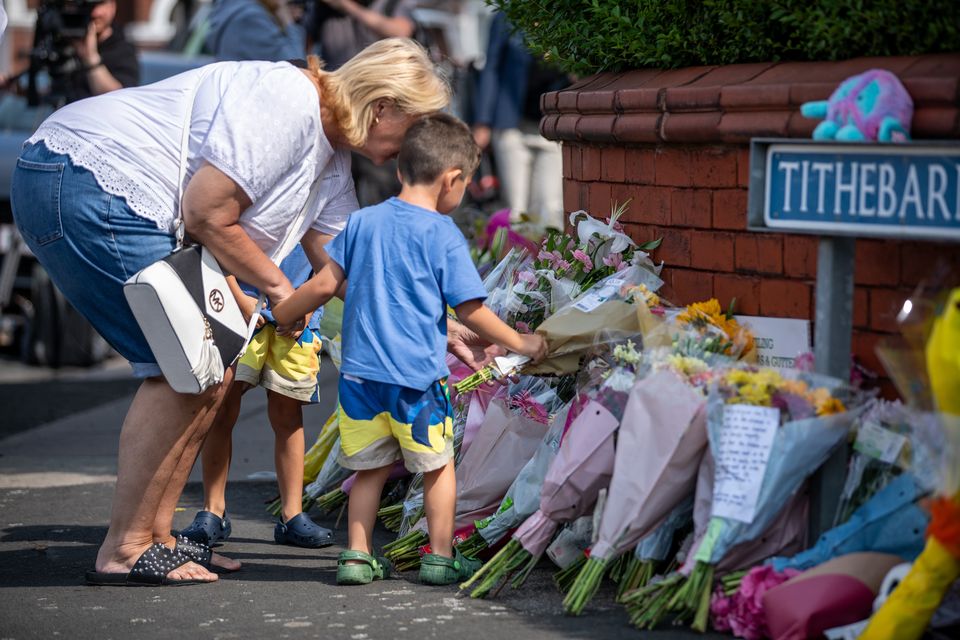 A child puts flowers on a pile of tributes near Hart Street (James Speakman/PA)