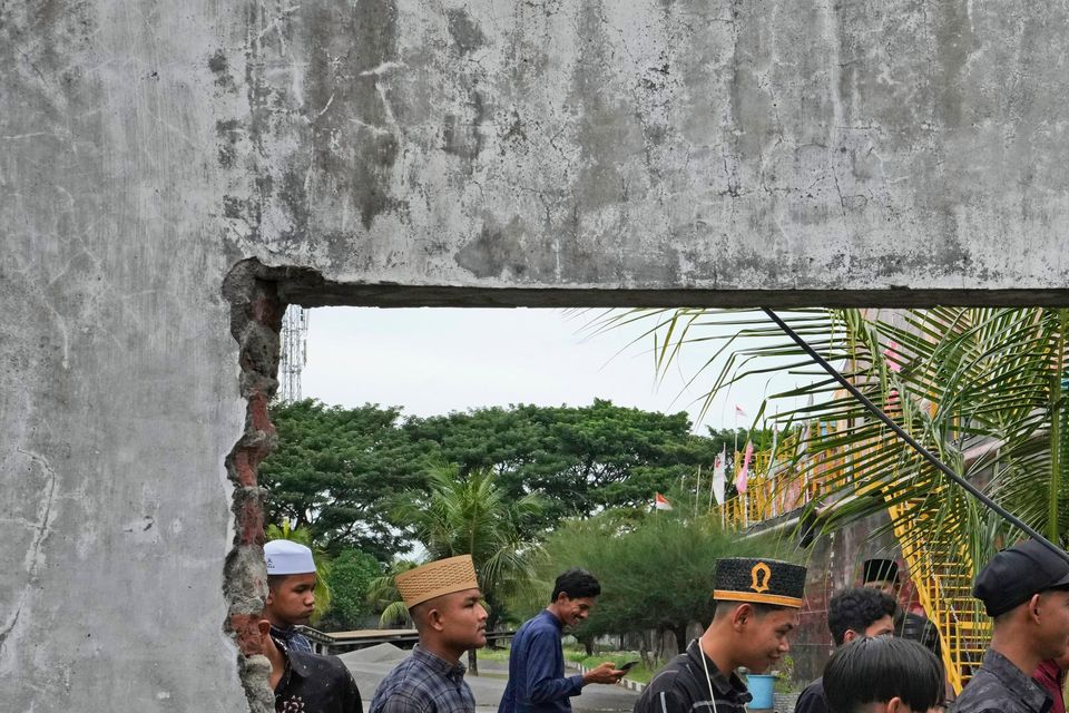 People are seen through a hole in the wall of a building damaged by the tsunami in Banda Aceh (Achmad Ibrahim/AP)