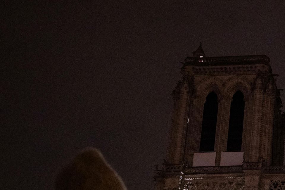 People watch Notre Dame Cathedral after a procession to bring the Virgin Mary statue from Saint-Germain l’Auxerrois church to the cathedral in Paris (Louise Delmotte/AP)