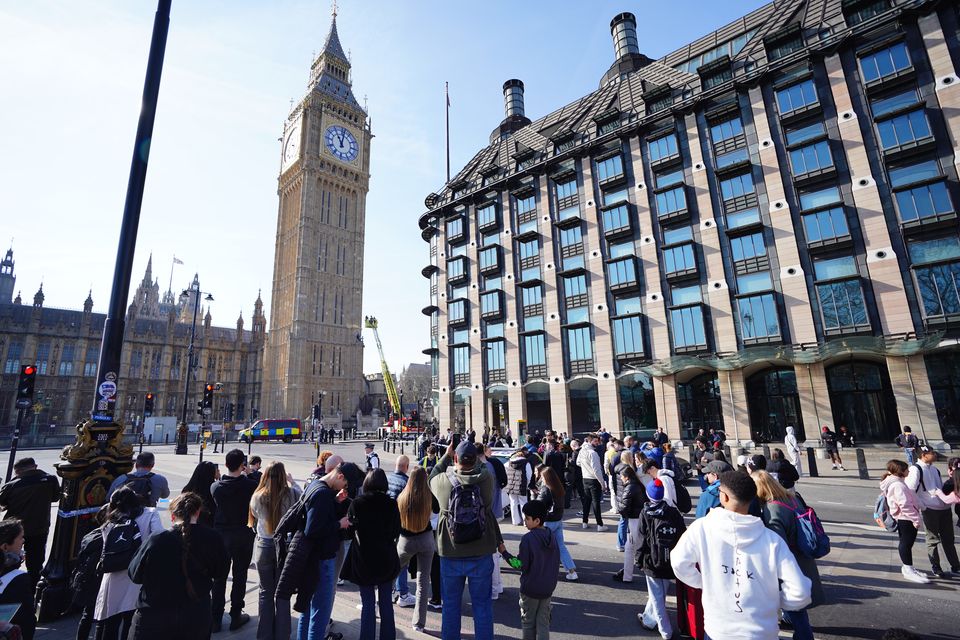 People watch a man with a Palestine flag after he climbed up Elizabeth Tower, which houses Big Ben at the Palace of Westminster in London (James Manning/PA)