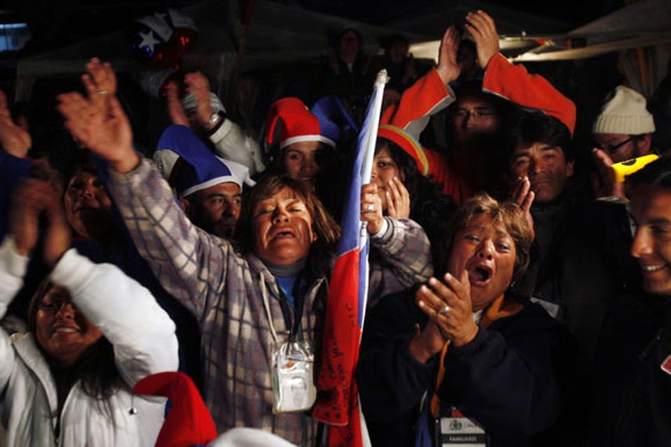 Relatives and friends of trapped miners celebrate while watching on a TV screen the rescue operation of Florencio Avalos at the camp outside the San Jose mine near Copiapo, Chile.