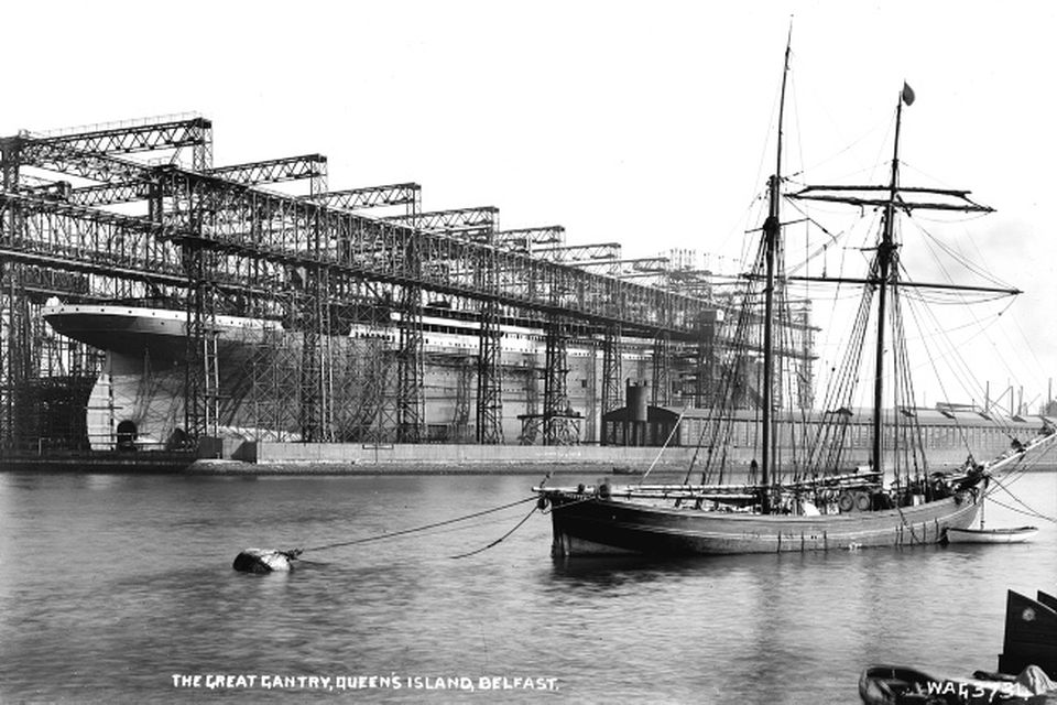 Titanic. The Great gantry, Queen's Island, Belfast. This photograph shows the enormous scale of the ship, together with the complex structure of the enfolding steel gantry, from which she will soon be free. The photograph also reflects old and new maritime technologies, with the traditional wooden schooner in the foreground contrasting eith the modernity ot Titanic. Photograph © National Museums Northern Ireland. Collection Harland & Wolff, Ulster Folk & Transport Museum