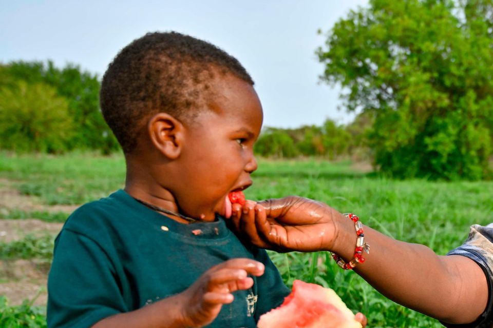 Amani feeding watermelon to her three-year-old son Badu which she has grown on the plot she has rented using the profit from her restaurant. Credit: David Macharia, Christian Aid