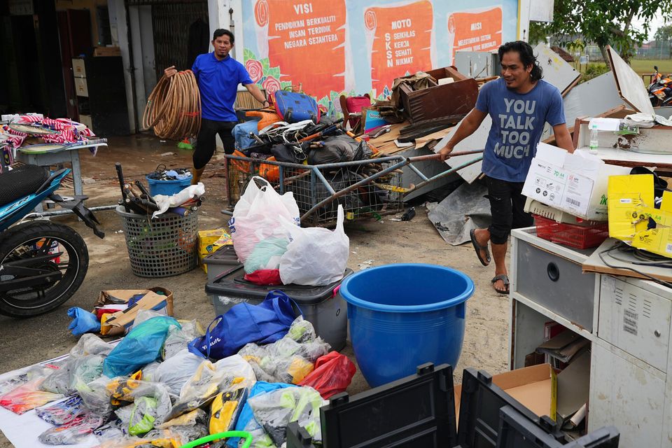 Men remove items from a school affected by a flood in Tumpat, on the outskirts of Kota Bahru, Malaysia (Vincent Thian/AP)